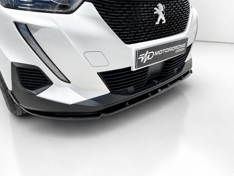 Close-up of a white Peugeot front end, showing the grille, headlight, and lower bumper with a designer plate.