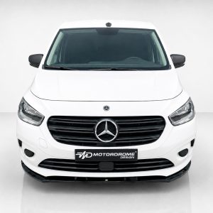 Front view of a white Mercedes-Benz van in a studio setting, displaying the black grille and emblem with a Motordrome Design plate on the bumper.