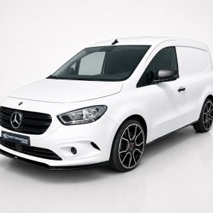 White Mercedes-Benz small cargo van photographed in a studio, showing the front and passenger side with black grille and alloy wheels.