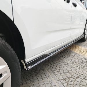 Close-up of a white van's side, showing the running board, front wheel, and a taped repair at the lower door edge on a patterned pavement.