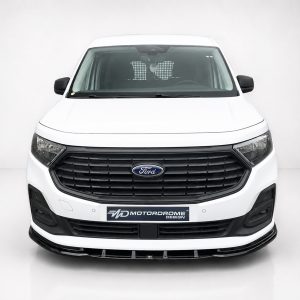 Front view of a white Ford commercial van in a studio setting, showing a black grille, headlights, and a Motordrome Design plate on the front bumper with the Ford emblem visible.