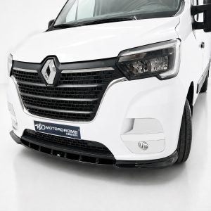 White van front close-up showing a prominent black grille and diamond-shaped badge in a studio setting (advertising/brand display).