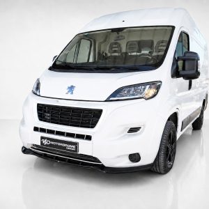 Front-left three-quarter view of a white Peugeot van with black grille and LED headlights, indoors on a glossy floor (Motordrome Design plate).