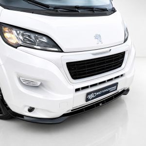 Front-left view of a white Peugeot van, displaying the headlight, emblem, and large grille