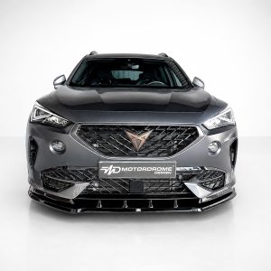 Front view of a dark gray SUV in a studio, highlighting a large black mesh grille with a bronze emblem and sharp LED headlights