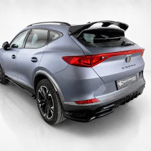 Rear-right three-quarter view of a metallic blue SUV with a large tail light strip and roof spoiler in a studio setting.