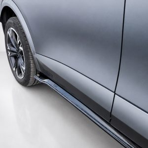 Close-up of a metallic blue car's side, featuring a stylish alloy wheel and lower side panel.