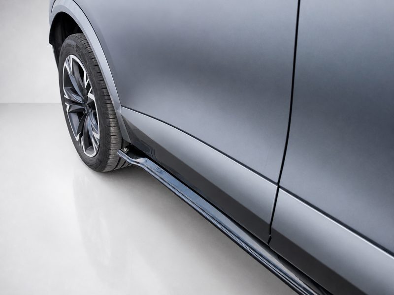 Close-up of a metallic blue car's side, featuring a stylish alloy wheel and lower side panel.