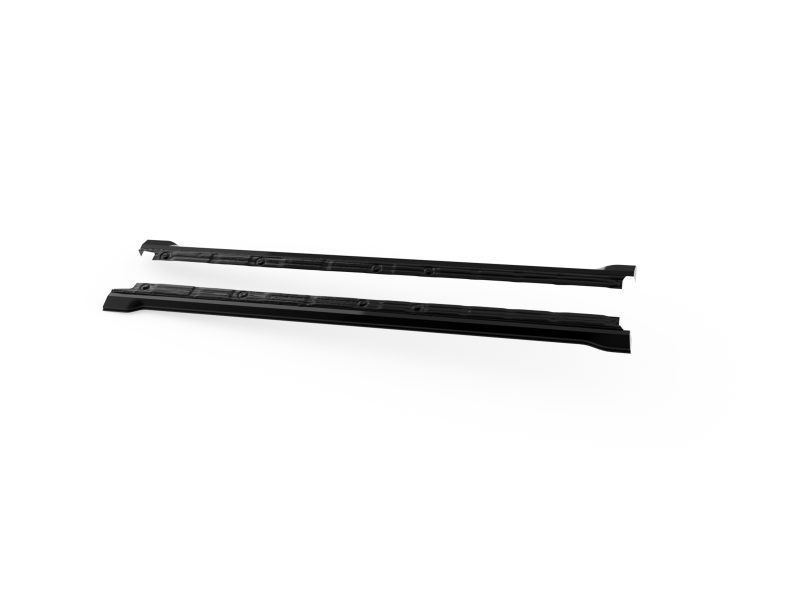 Two black roof rack crossbars laid out on a white background, likely vehicle roof racks ready for installation