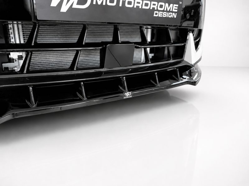 Close-up of a glossy black car front with a bold grille and custom bumper design, showing a small WD logo plate.