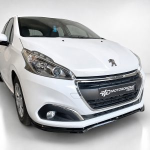 K209-001_3jpg - OPSHOLDERS White Peugeot hatchback photographed in a studio, front three-quarter view showing the grille and emblem, with a MotorDrome Design plate on the bumper.