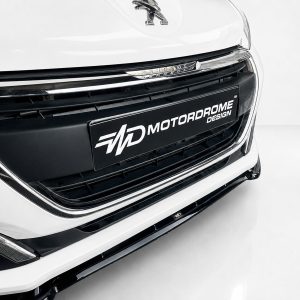K209-001_4jpg - OPSHOLDERS Close-up of a white car's front grille with chrome accents and a black license plate reading MOTORDROME DESIGN.
