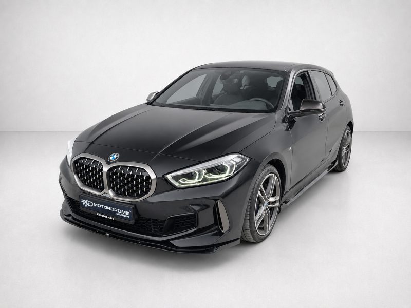Black BMW sedan in a studio setting, shown from a front three-quarter angle focusing on the grille and headlights