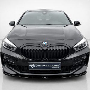Front view of a glossy black BMW SUV in a studio, showing the signature kidney grille and badge with a MD MotorDrome Design plate.