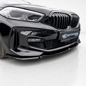 Close-up of a glossy black car front with prominent kidney grille and headlight, featuring a Motordrome Design plate.