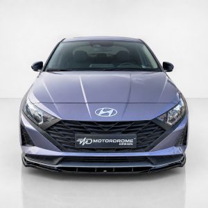 Front view of a metallic purple Hyundai sedan in a studio, showcasing the grille and Hyundai logo with a showroom backdrop showing the MD Motordrome Design plate.