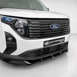 Front close-up of a white Ford pickup truck’s front end, showing the black grille and emblem with a Motordrome Design plate