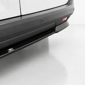 Close-up of the rear bumper and running board of a white SUV, with a small logo plate on the step.