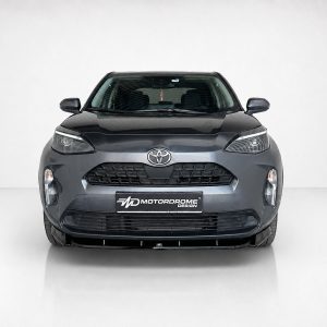 Front view of a gray Toyota crossover facing the camera in a studio setup, with a black grille and prominent Toyota emblem on the hood.