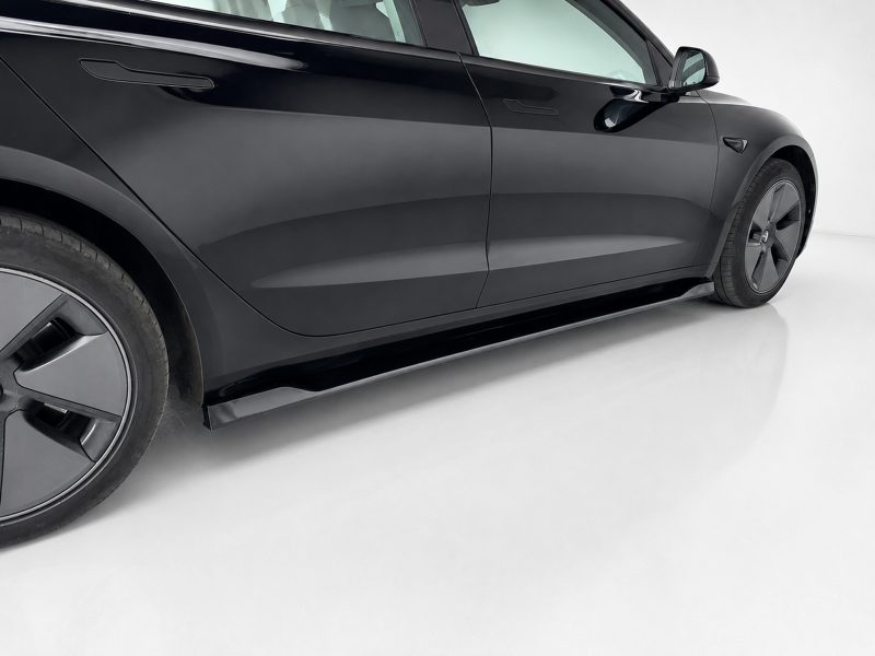 Side view of a sleek black car with flush door handles and large alloy wheel on a light surface