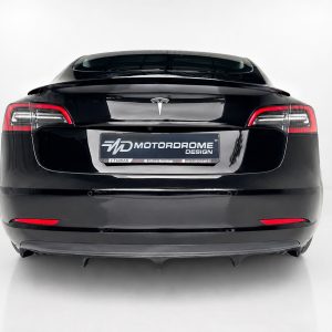 K214-004_2jpg - OPSHOLDERS Rear view of a glossy black electric car with distinctive taillights and a Motordrome Design license plate area on a white studio backdrop