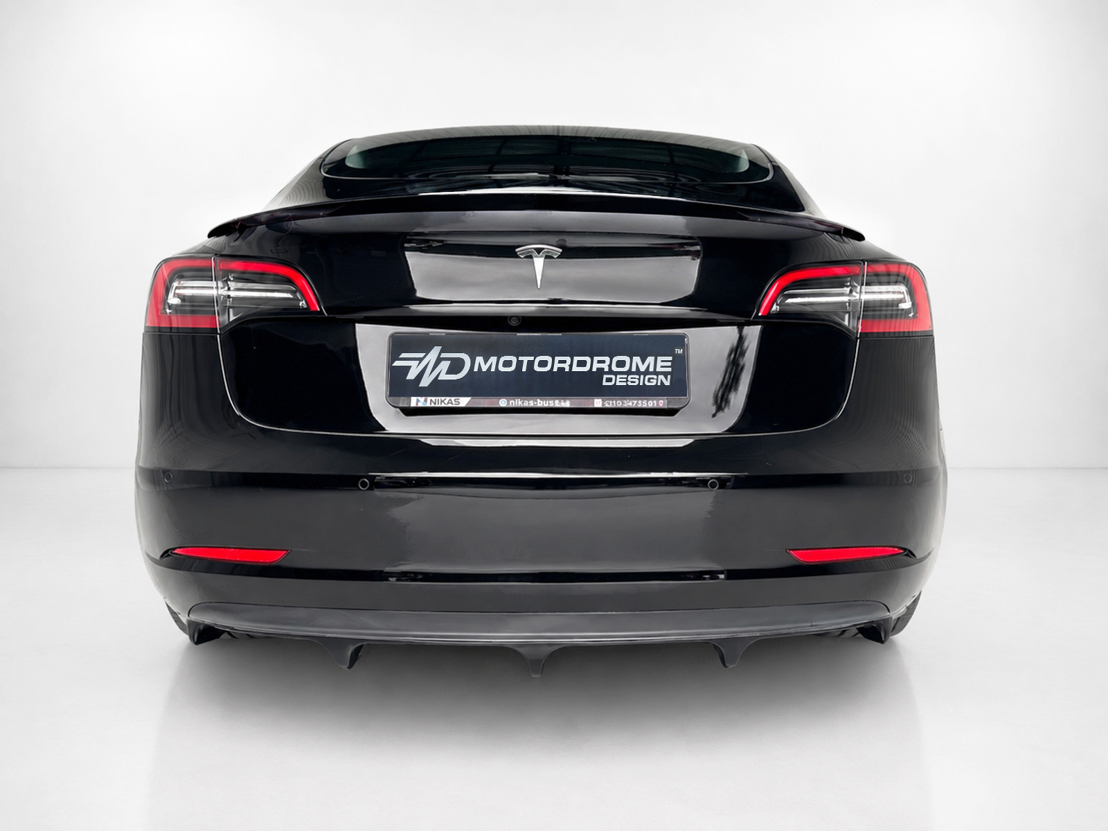 K214-004_2jpg - OPSHOLDERS Rear view of a glossy black electric car with distinctive taillights and a Motordrome Design license plate area on a white studio backdrop