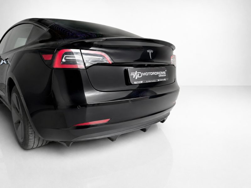 K214-004_3jpg - OPSHOLDERS Rear view of a sleek black sedan in a white studio, showing taillights and a license plate reading 'Motordrome Design' (custom plate).