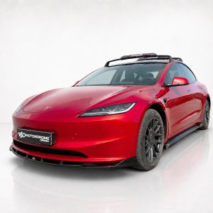 Red electric car with a roof rack photographed in a white studio background, front-left angle view, glossy finish.