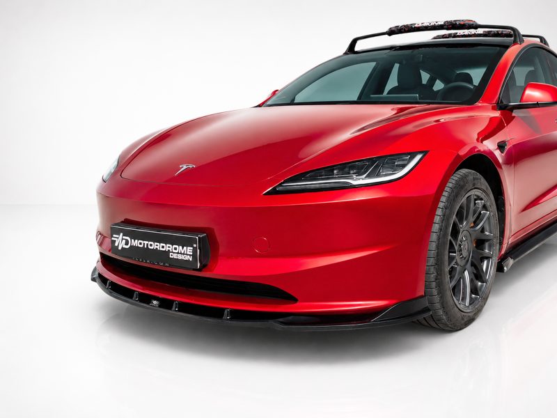 Front-left view of a bright red sports car with a sleek, aerodynamic design and a Motordrome Design license plate