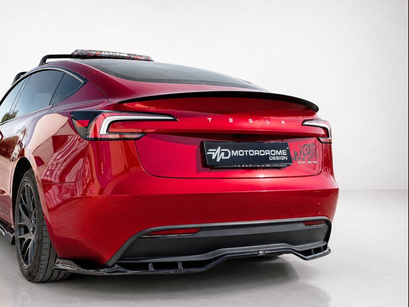 Rear view of a red Tesla with a black decorative plate reading MOTORBOME DESIGN and a sporty rear diffuser.