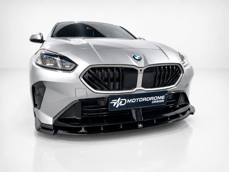 Front view of a silver BMW car in a studio, highlighting the large kidney grille and sculpted bumper.