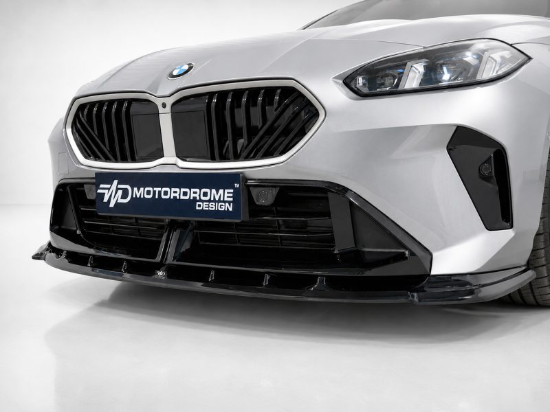 Close-up of a silver car front with a bold black grille and a Motordome Design plate visible on the bumper