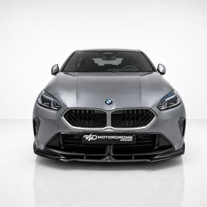Front view of a silver sedan in a studio, showing a bold black grille and the MOTORDROME DESIGN plate on the bumper