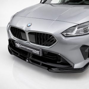 Front view of a silver BMW with prominent dual-kidney grille, headlight, and a Motordrome Design plate on the bumper.