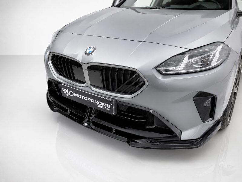 Front view of a silver BMW with prominent dual-kidney grille, headlight, and a Motordrome Design plate on the bumper.