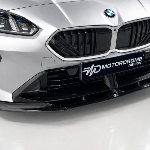 Close-up of a silver BMW car front showing the prominent black kidney grille, headlight, and a MOTORDROME DESIGN plate below the grille.