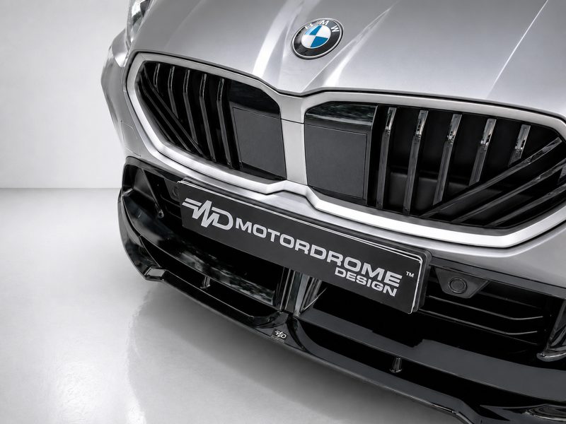 Close-up of a silver BMW front end, showing the badge and a black license plate with 'MD Motordome Design' text across it.