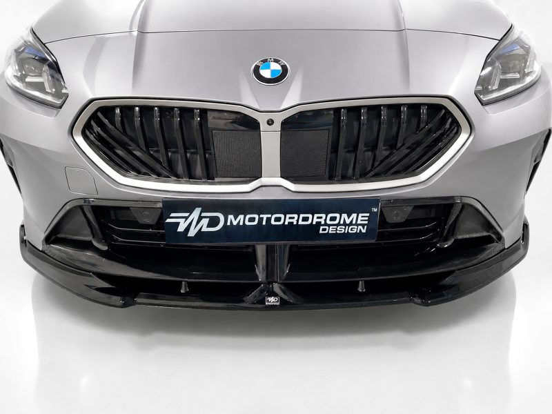 Front view of a silver BMW with a large black kidney grille and a Motordrome Design plate on the bumper.