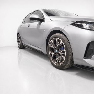 Silver BMW sedan, front-right three-quarter view in a studio, showing large alloy wheels and blue brake calipers.