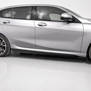 Side view of a silver BMW sedan with sporty alloy wheels and an M badge on the front door panel