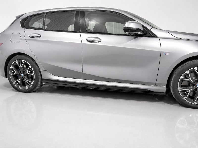 Side view of a silver BMW sedan with sporty alloy wheels and an M badge on the front door panel