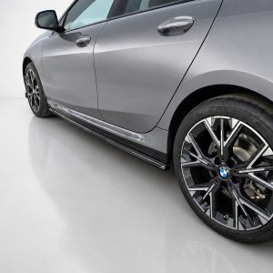 Silver BMW sedan side view focusing on alloy wheel and lower body panel.