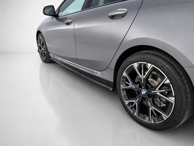 Silver BMW sedan side view focusing on alloy wheel and lower body panel.