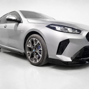 Silver BMW sedan in a studio, front-right view showing the bold grille and alloy wheels.