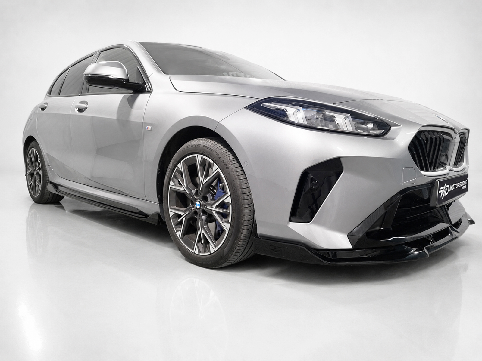 K215-004_1jpg - OPSHOLDERS Silver BMW sedan in a studio, front-right view showing the bold grille and alloy wheels.