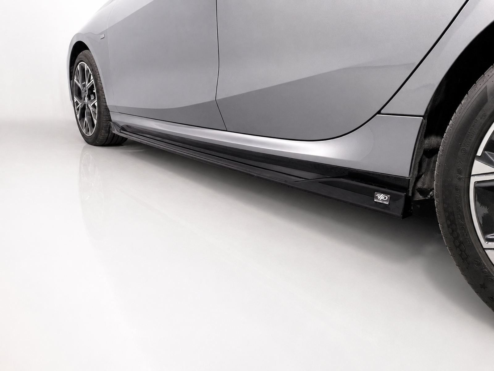 K215-004_2jpg - OPSHOLDERS Side view of a gray car highlighting the aerodynamic side skirt and alloy wheel on a clean floor surface.