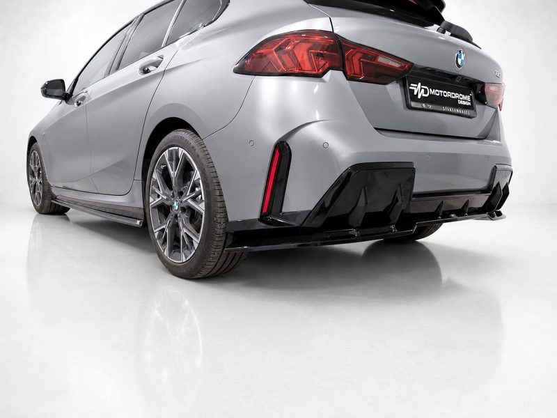 Rear three-quarter view of a silver BMW with an aggressive black-body kit and diffuser, parked on a white studio floor