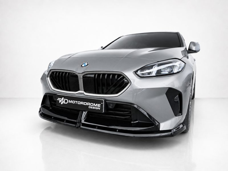 Front view of a silver sports car in a studio, highlighting its black grille and sleek headlights; MotorDrome Design plate visible on the bumper.