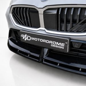 Close-up of a modern car front with a chrome-trimmed grille and a license plate reading MOTORDROME DESIGN.