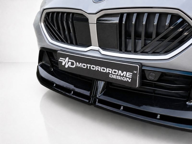 Close-up of a modern car front with a chrome-trimmed grille and a license plate reading MOTORDROME DESIGN.